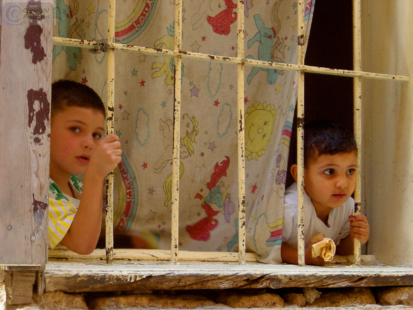 Two Boys Looking Through Bars in a Window in Saida